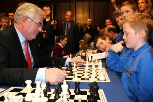 An Tánaiste Eamon Gilmore and Ollie from Gaelscoil Chnoc Liamhna get a lot of attention during their chess match in the Mansion House after Comórtas Fichille Cúige Laighean 2014 (during Garry Kasparov's visit to Ireland).